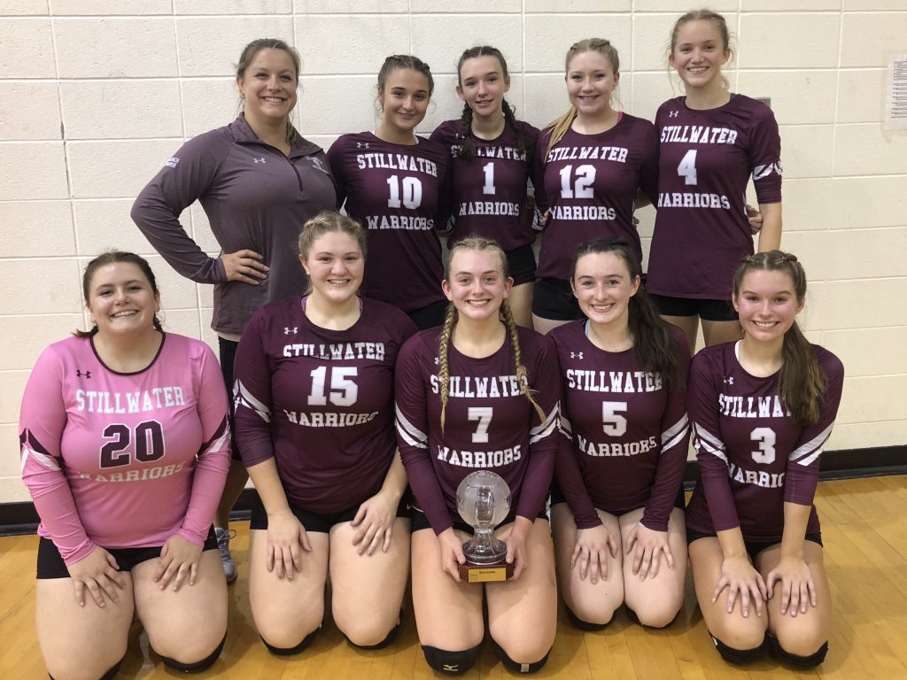 Volleyball team grouped together for photo, smiling at the camera