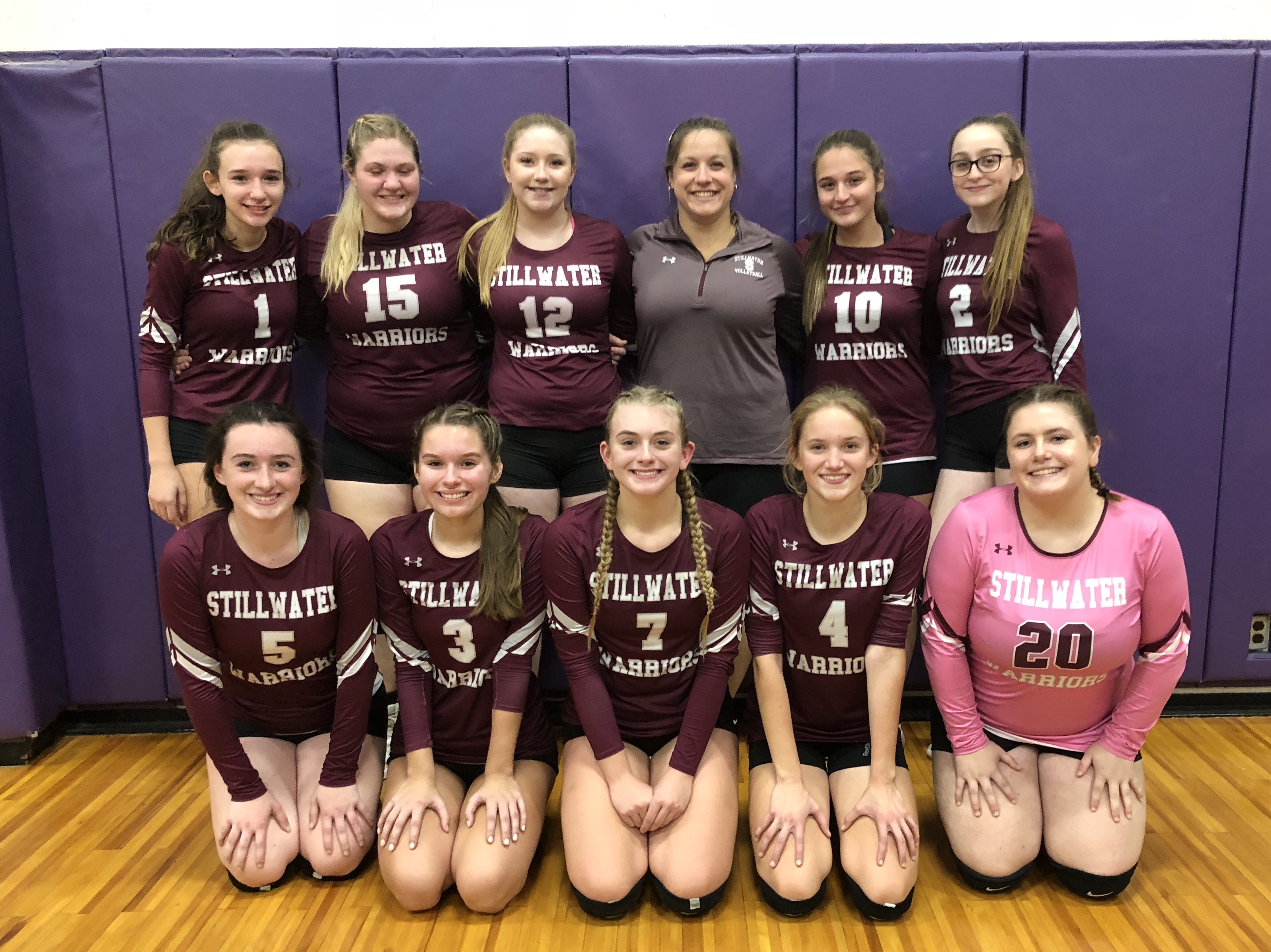 Varsity volleyball team standing in two rows posing for picture