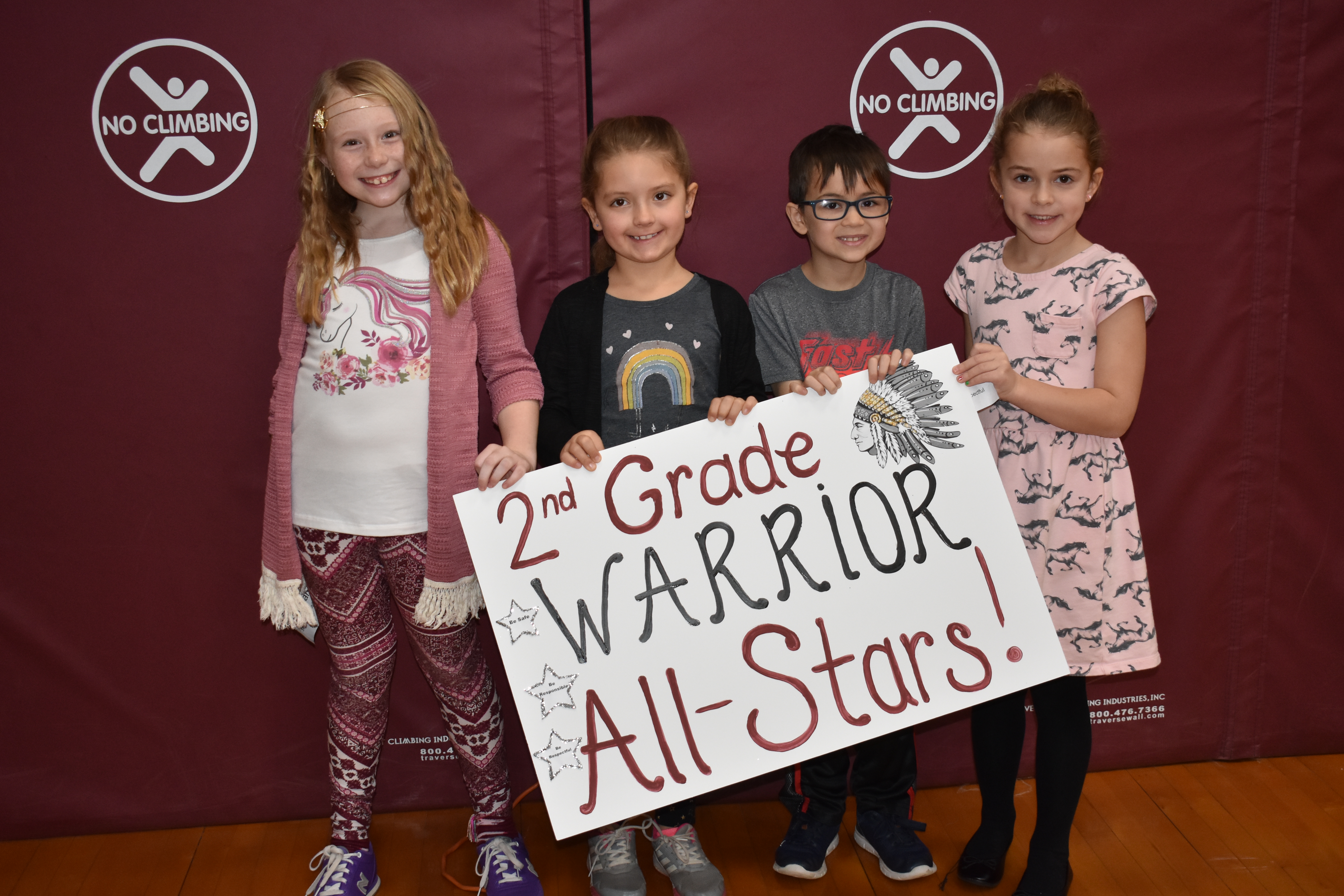 Students grouped together with a sign showing their grade level.