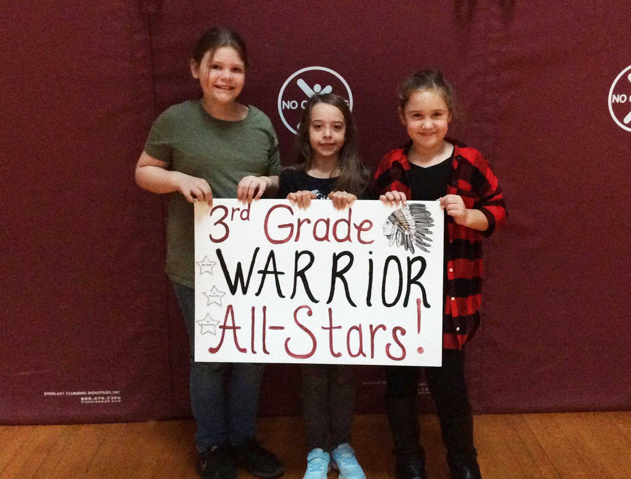 Students grouped together with a sign showing their grade level.