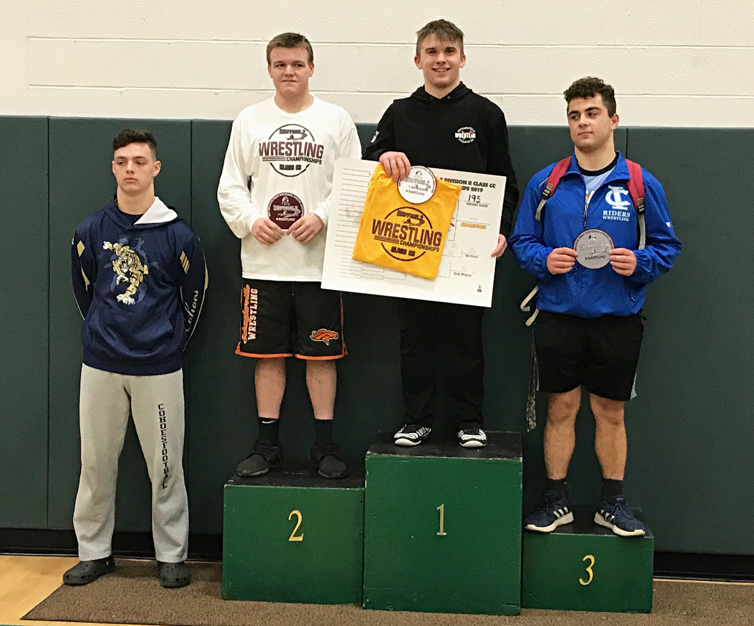 Four wrestlers on podium receiving awards