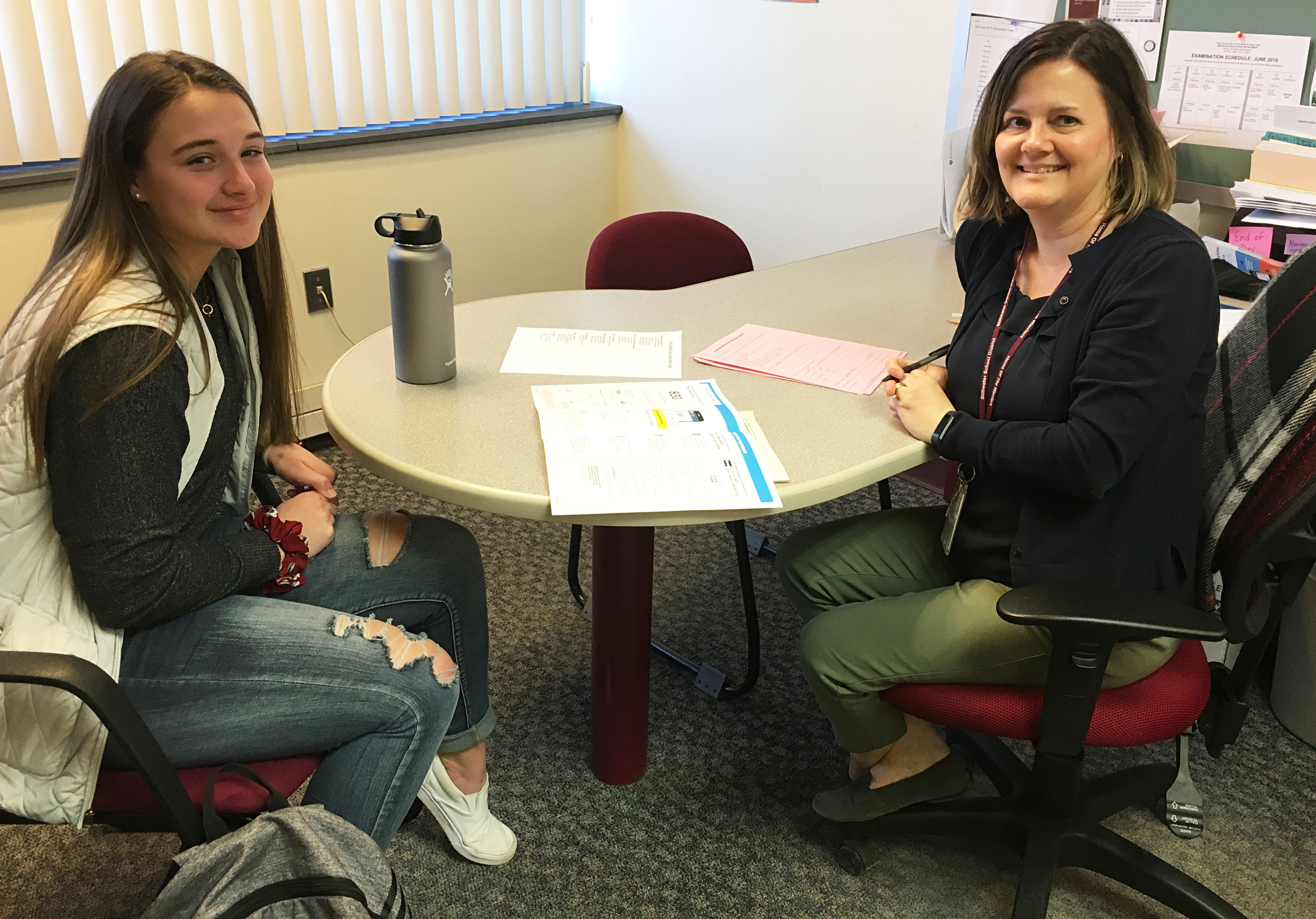 Teacher and student sitting at a table smiling at the camera