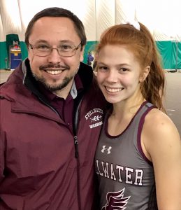 Athlete in track uniform posing with coach