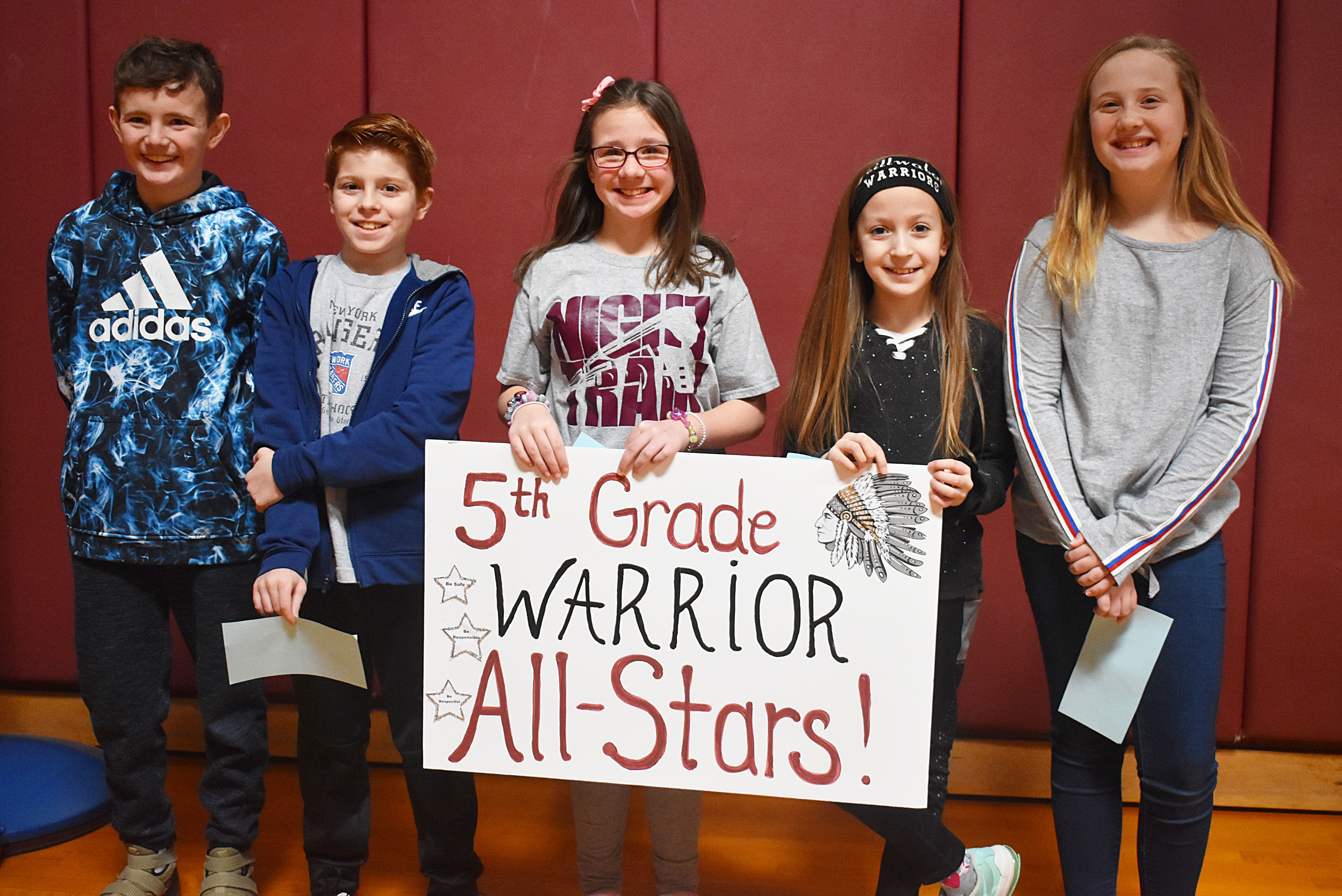 A group of students standing with a fifth grade sign