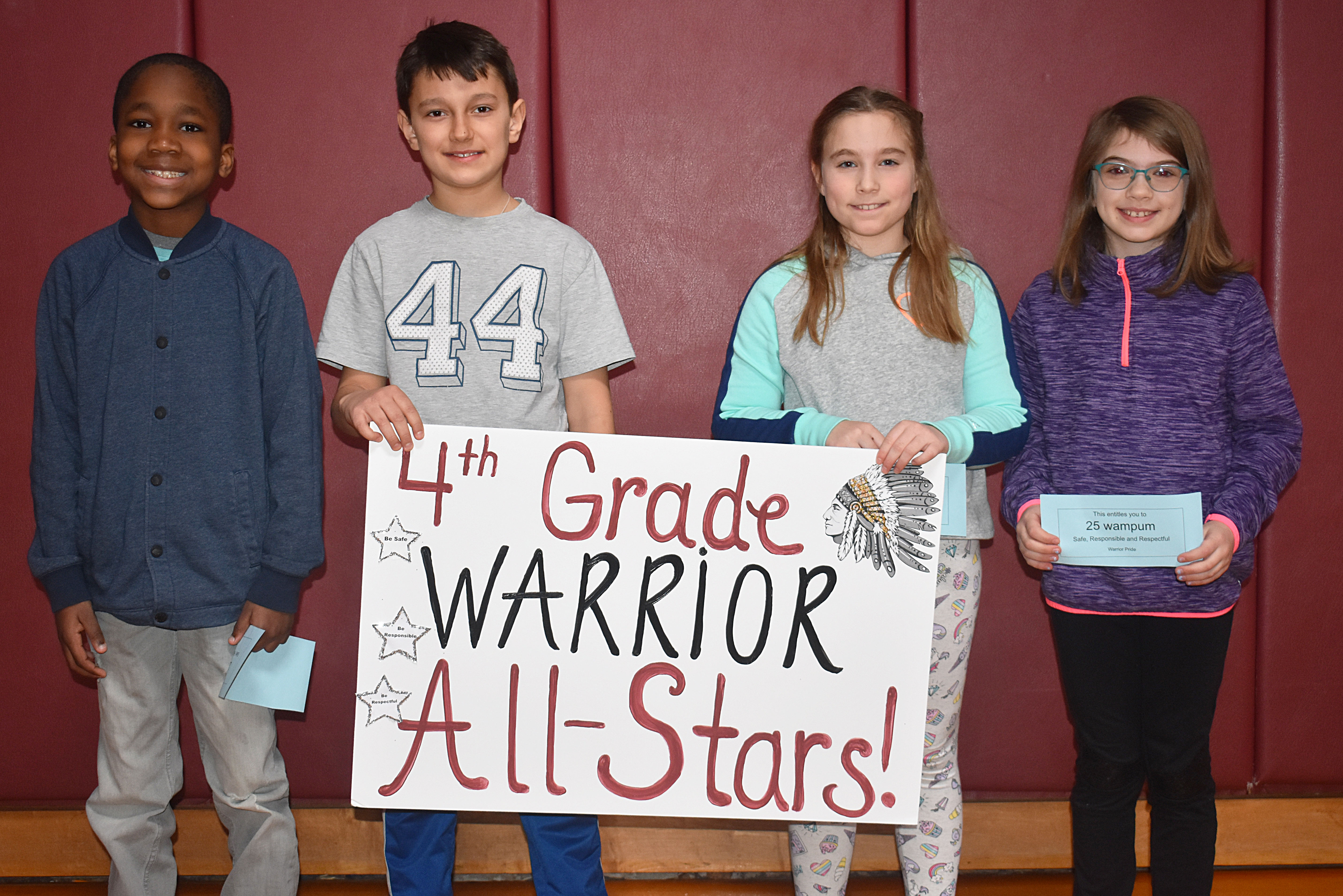 A group of students standing with a fourth grade sign