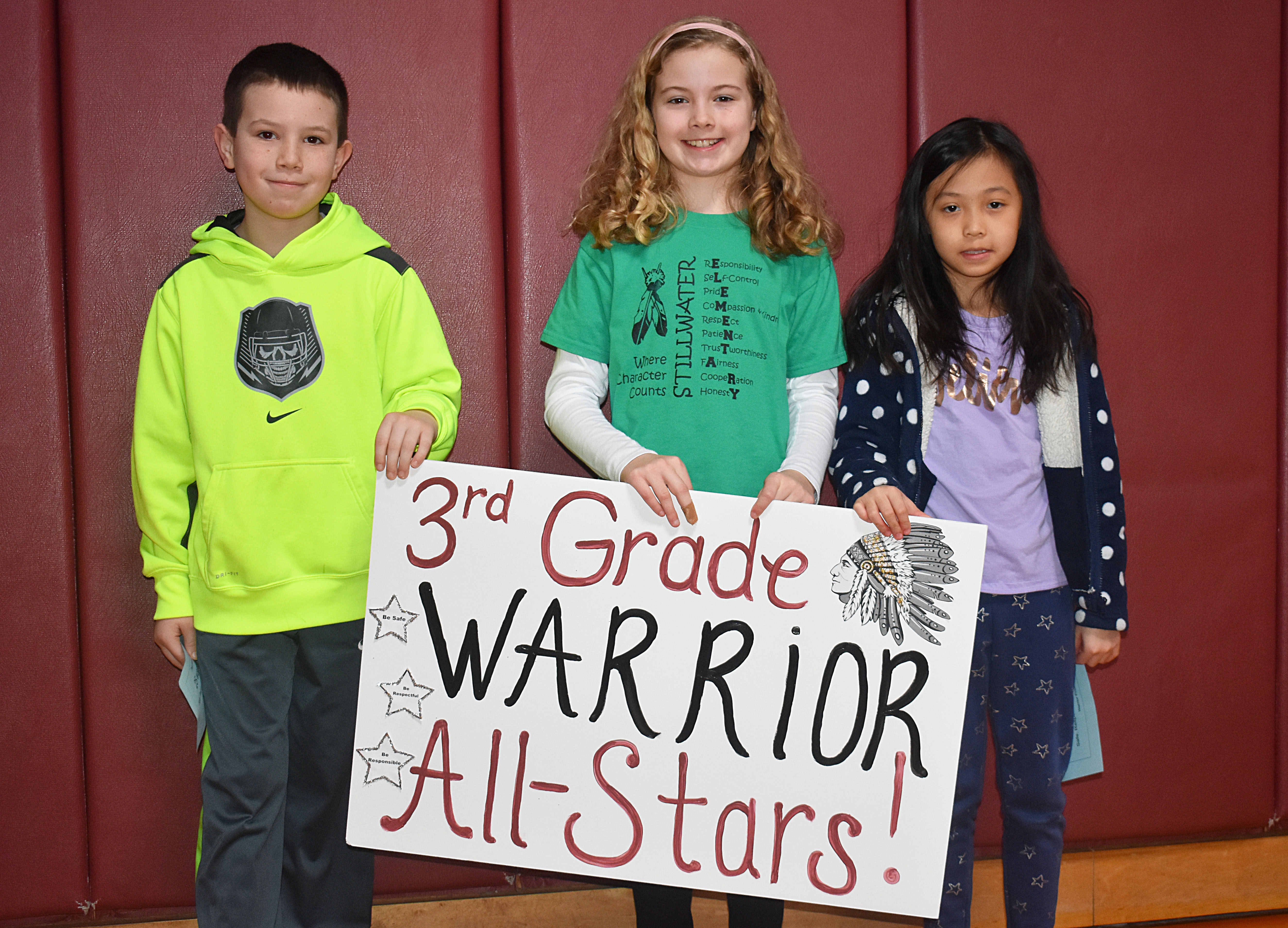 A group of students standing together with a third grade sign