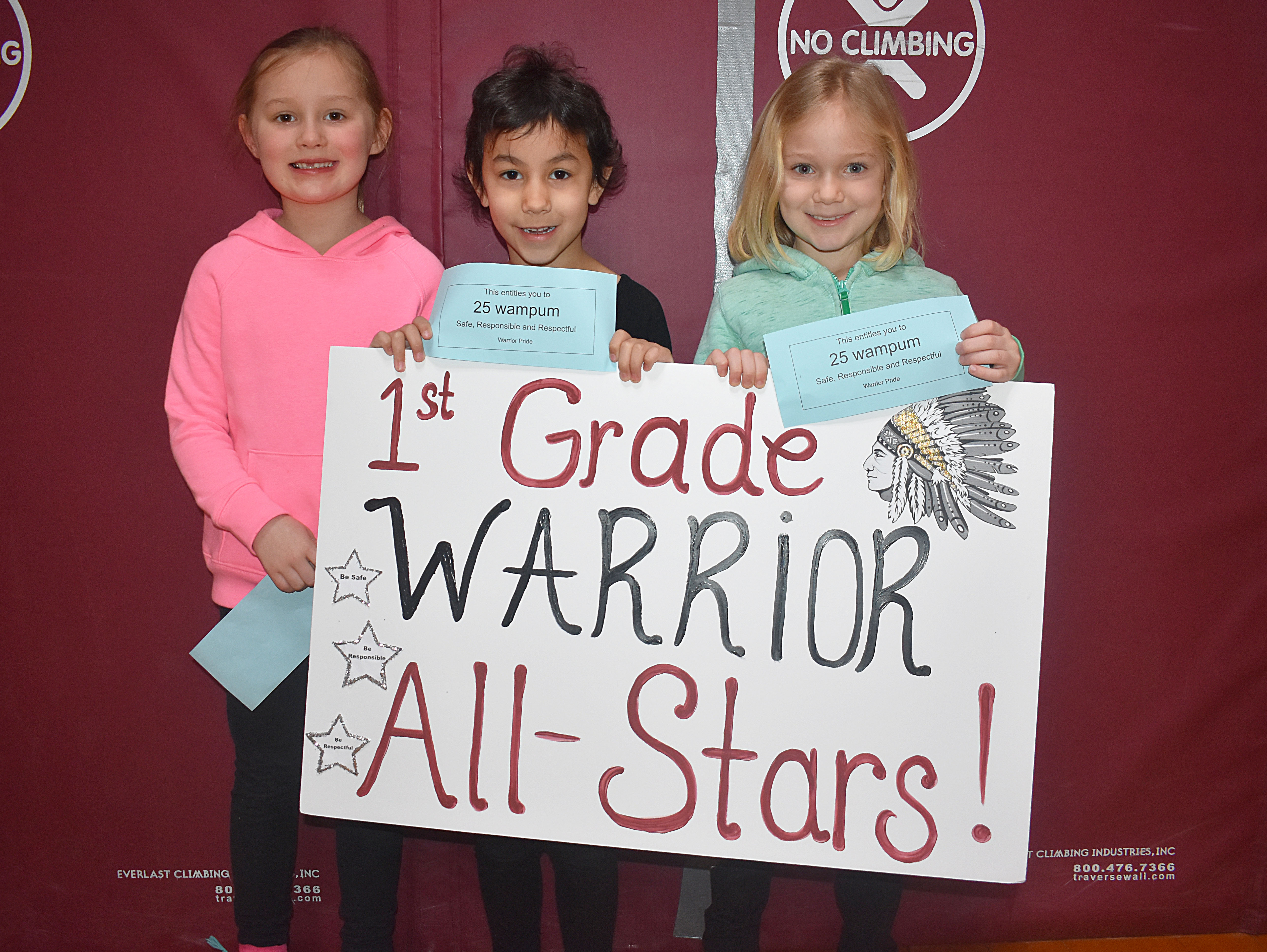 Three students standing together with a first grade sign