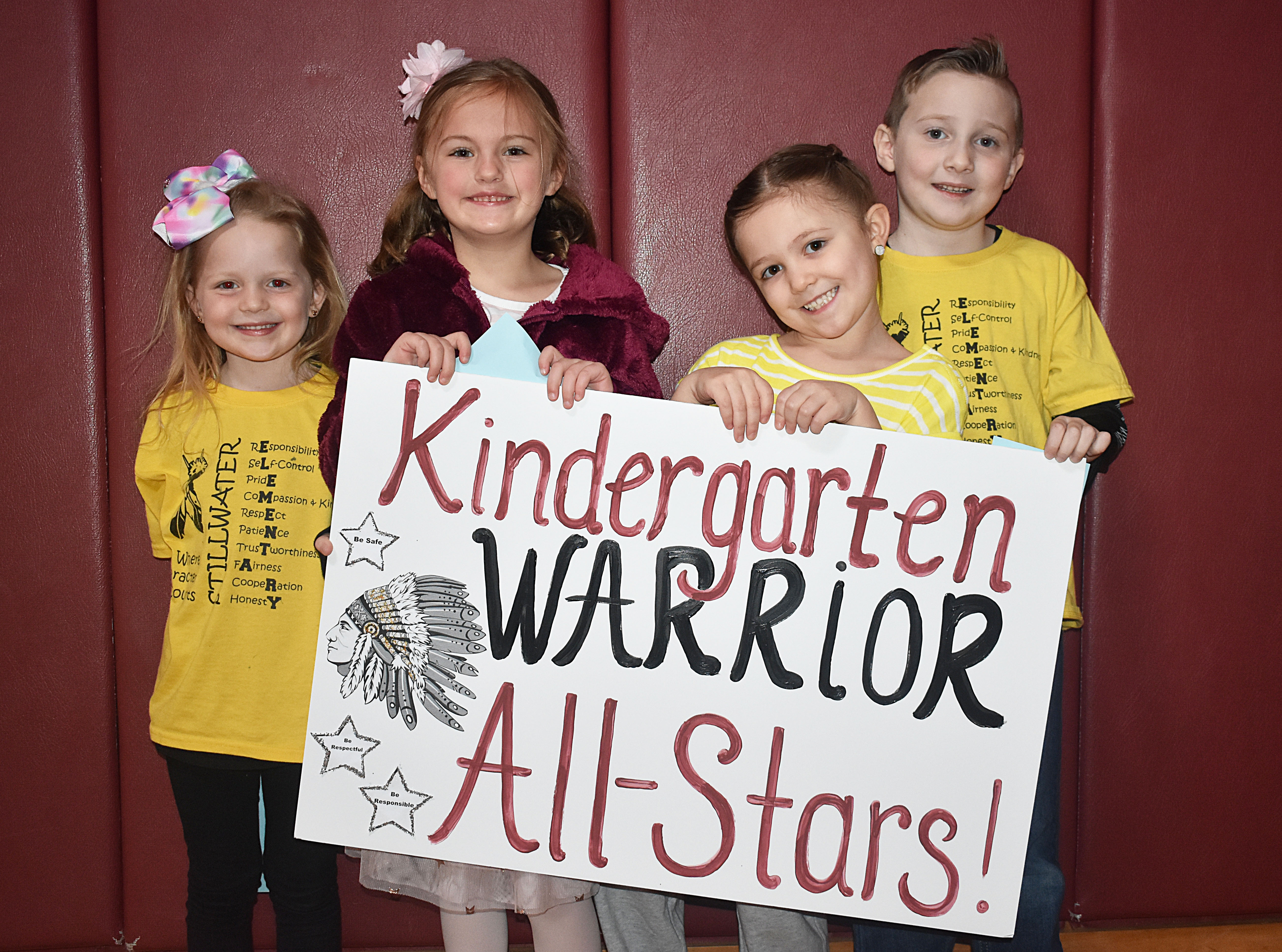 Four students standing in a row with a kindergarten sign