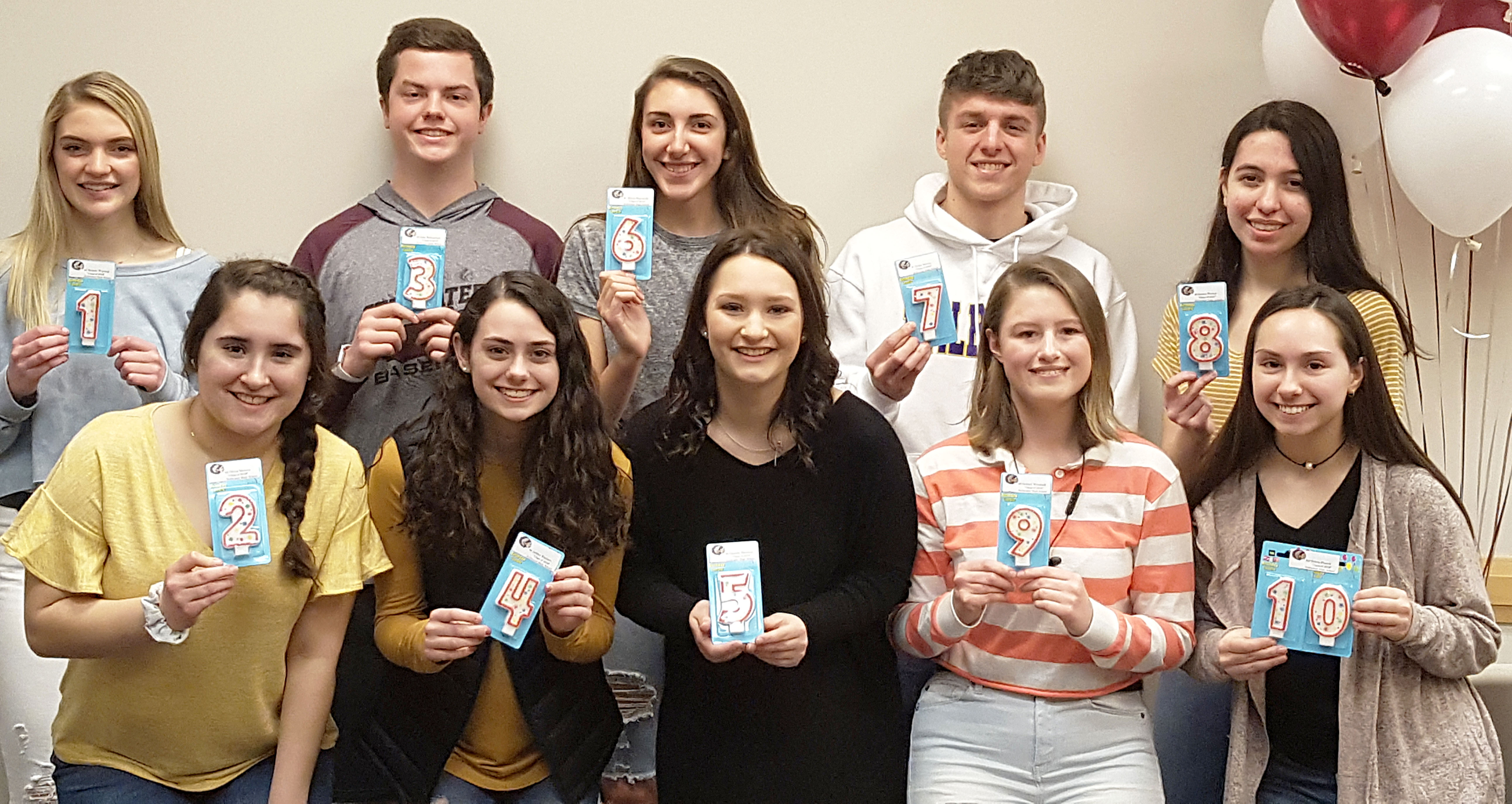 Top ten students gathered together for a photo holding up what number they rank.