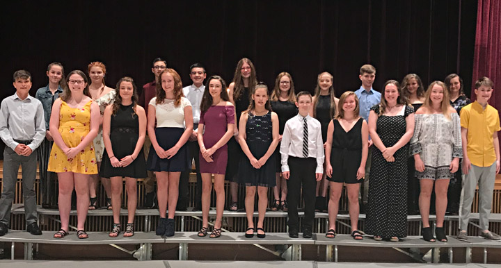 Group of students standing on risers smiling for a photo