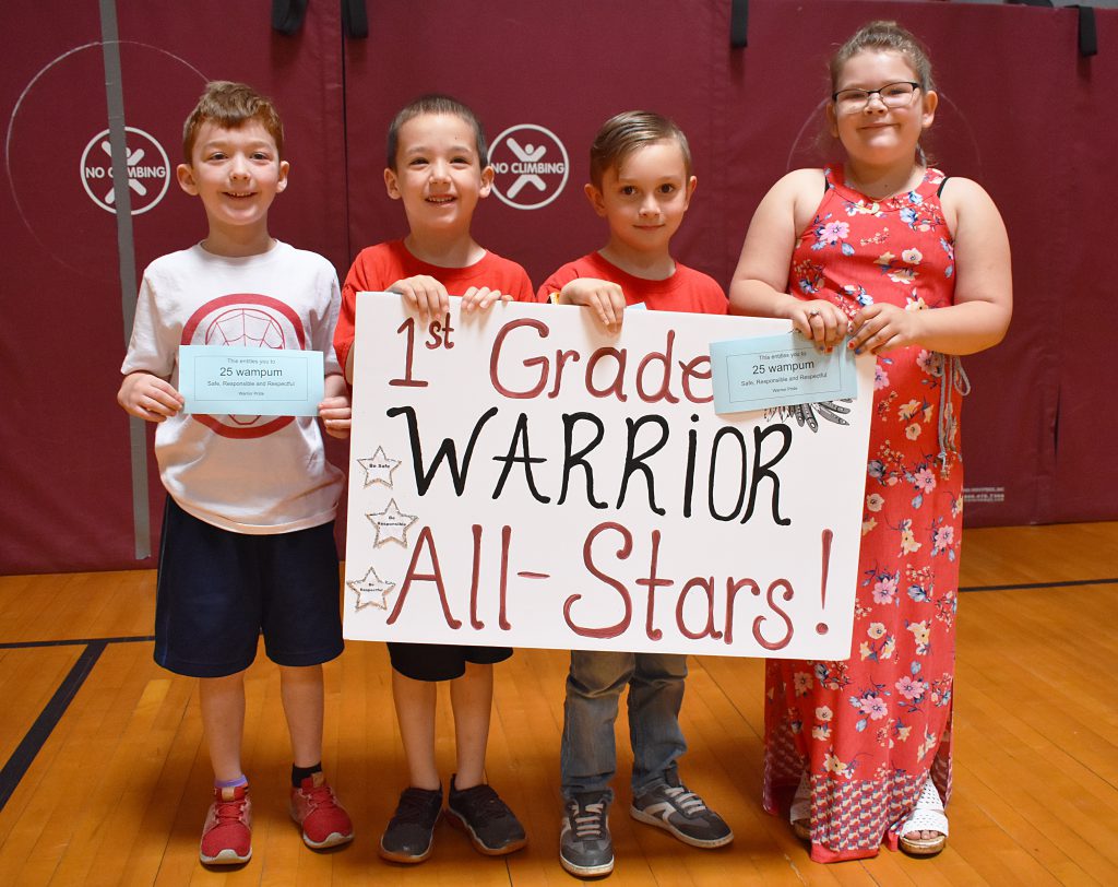 First grade students standing behind sign