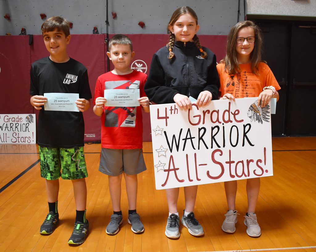 Fourth grade students standing behind sign