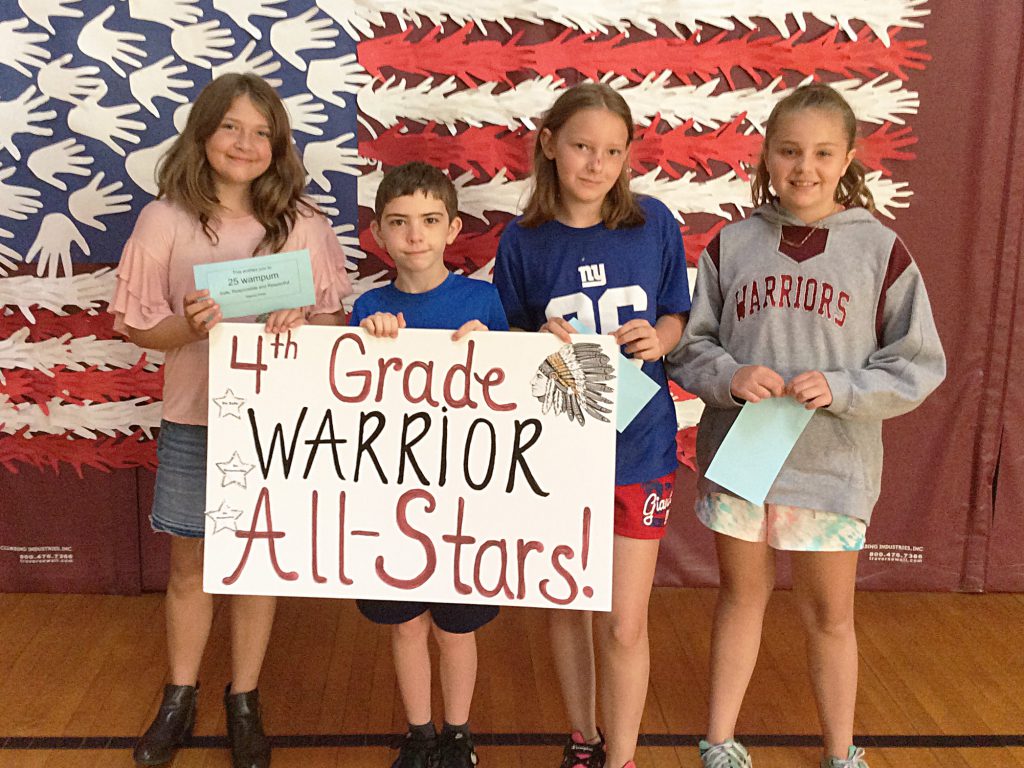 Three girls and a boy with fourth grade sign