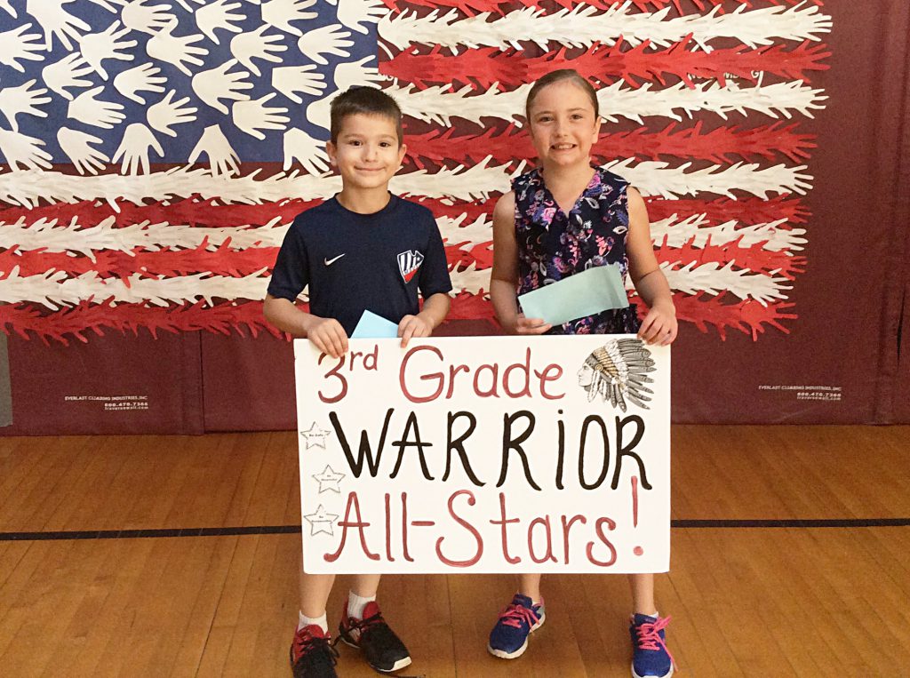 A boy and a girl with third grade sign