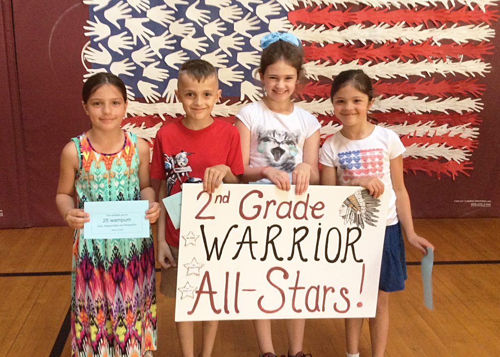 Three girls and a boy with second grade sign