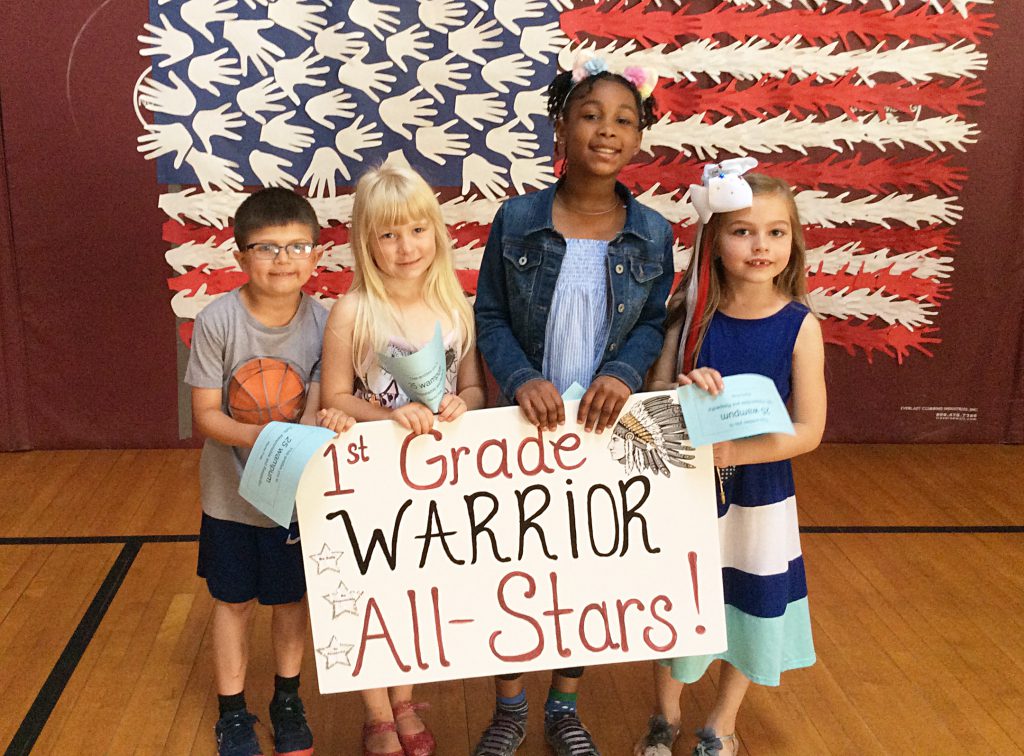 Three girls and a boy with first grade sign