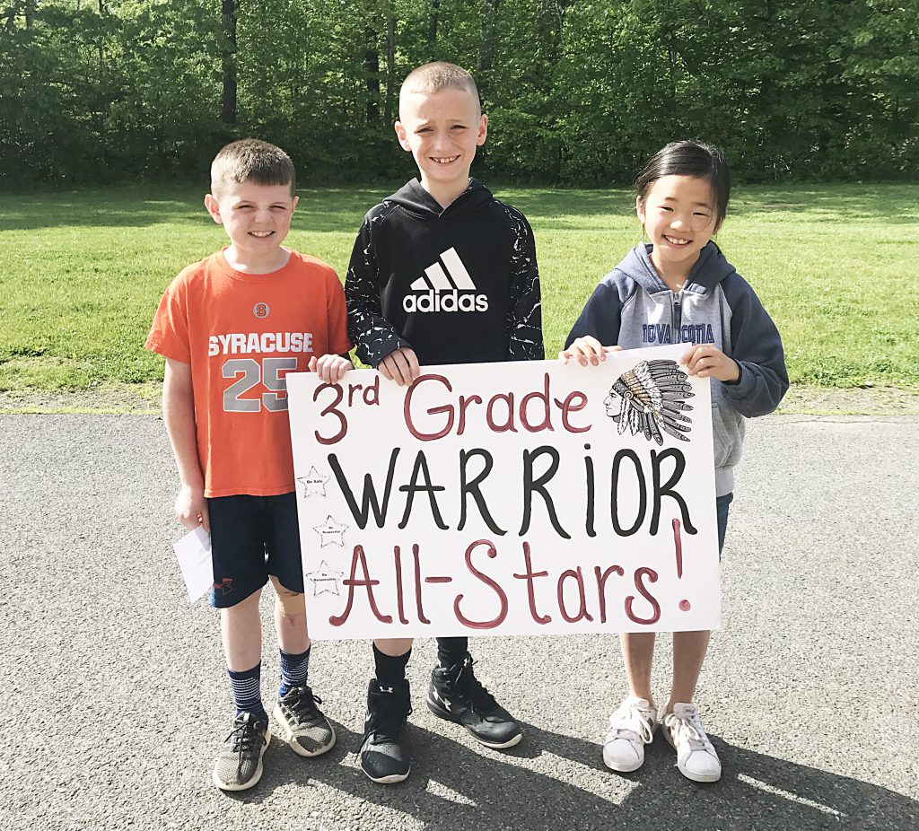 Three students standing behind sign