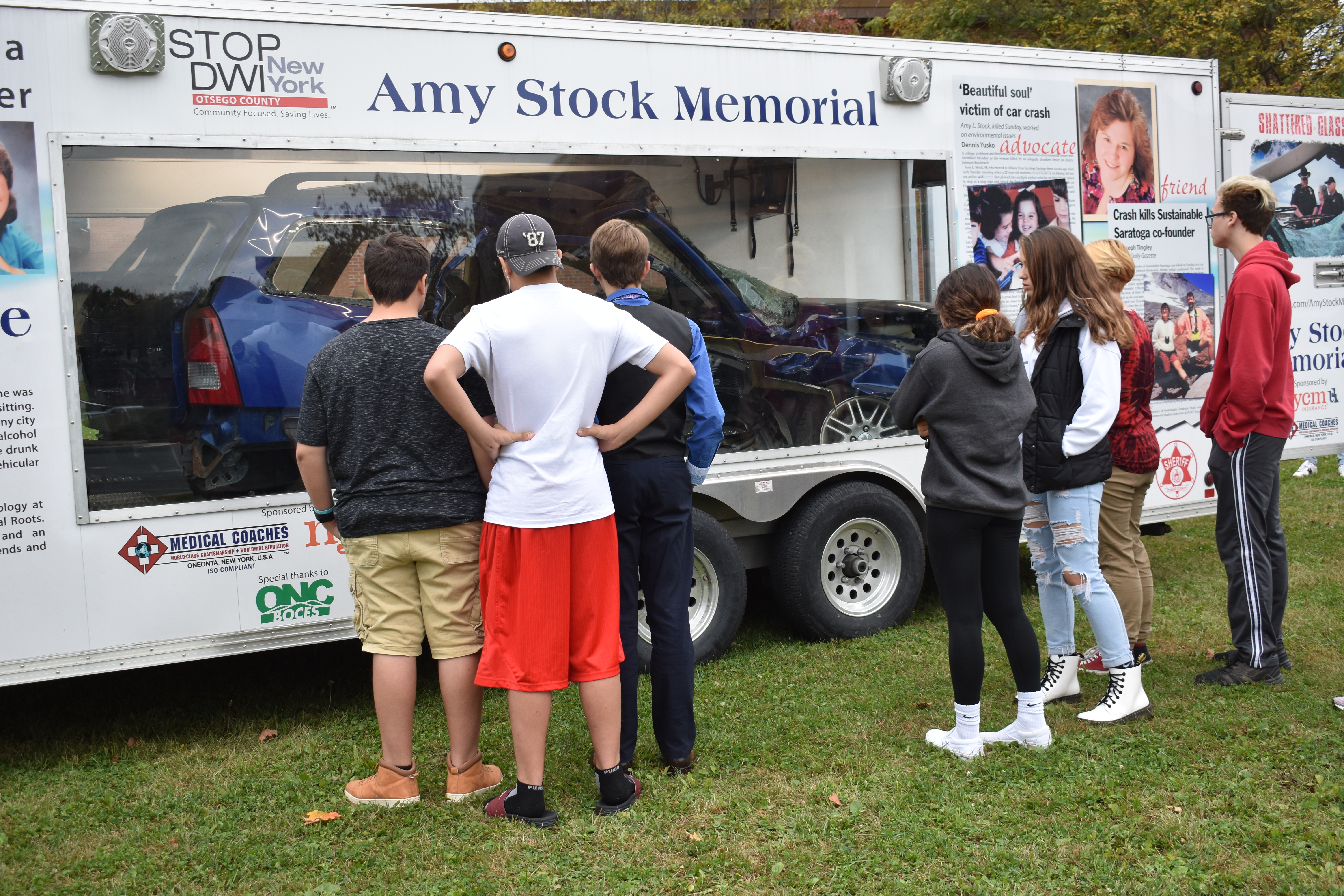 Students standing outside looking at memorial trailer