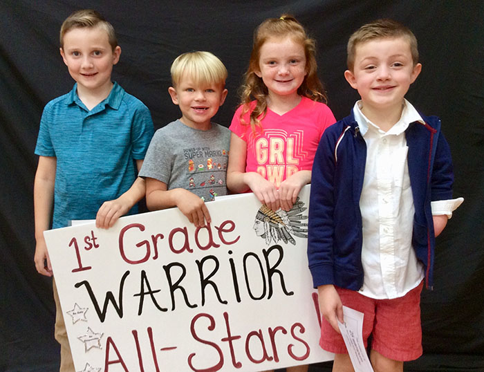 First grade warrior all stars standing with sign