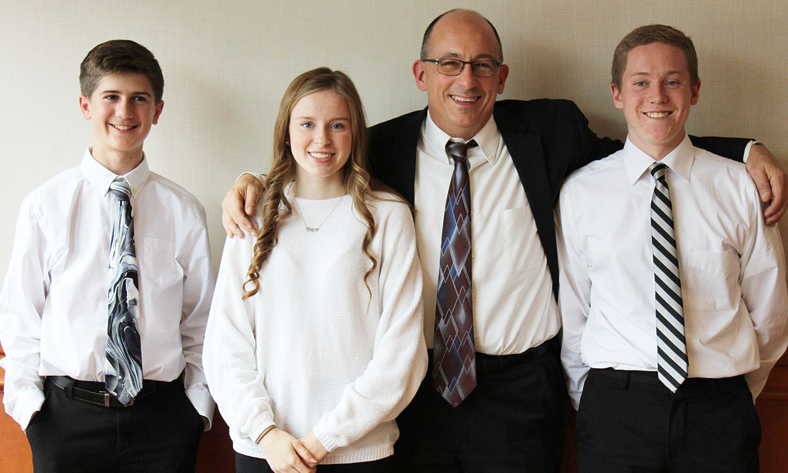 Three students wearing white shirts standing with their teacher