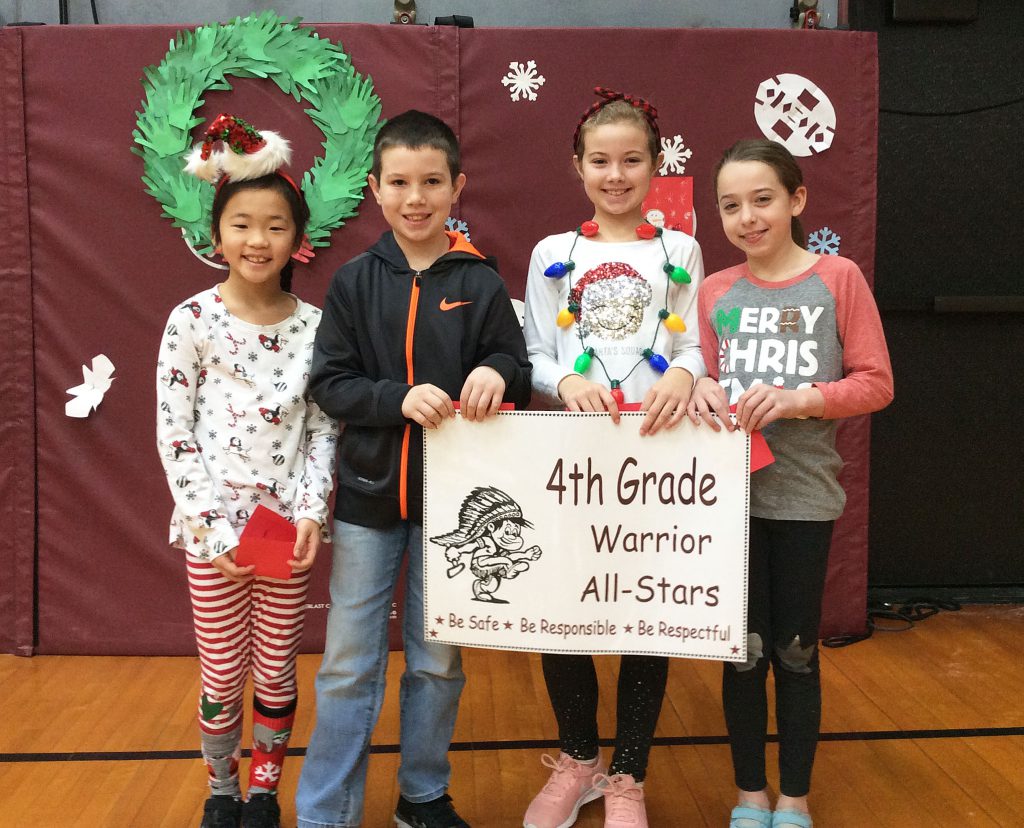 Four Fourth grade students standing with warrior sign