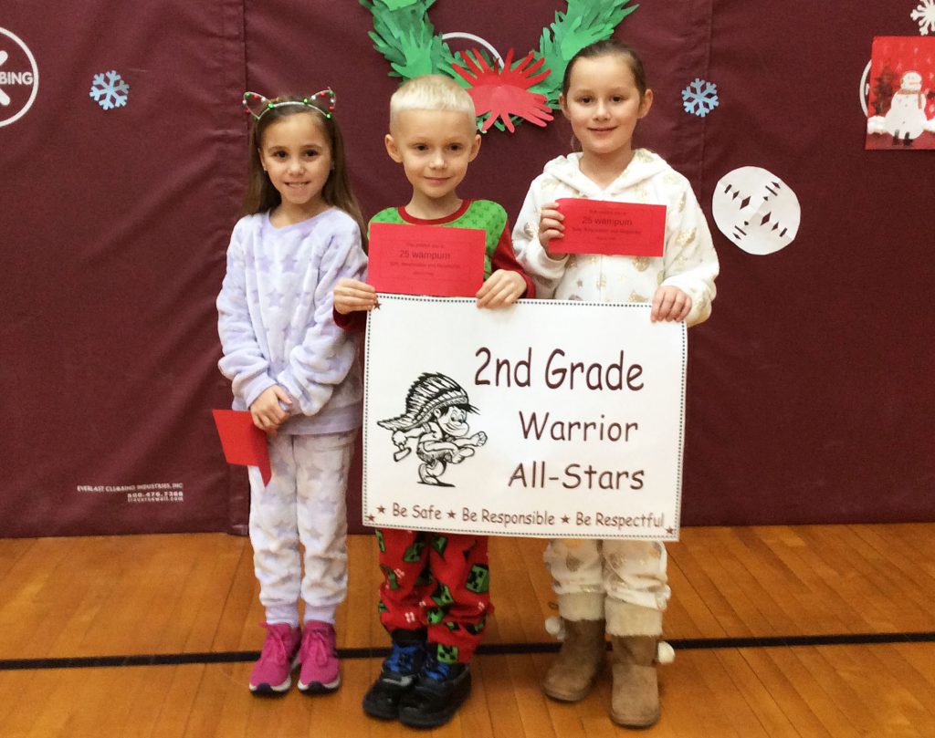 Three students standing with second grade sign