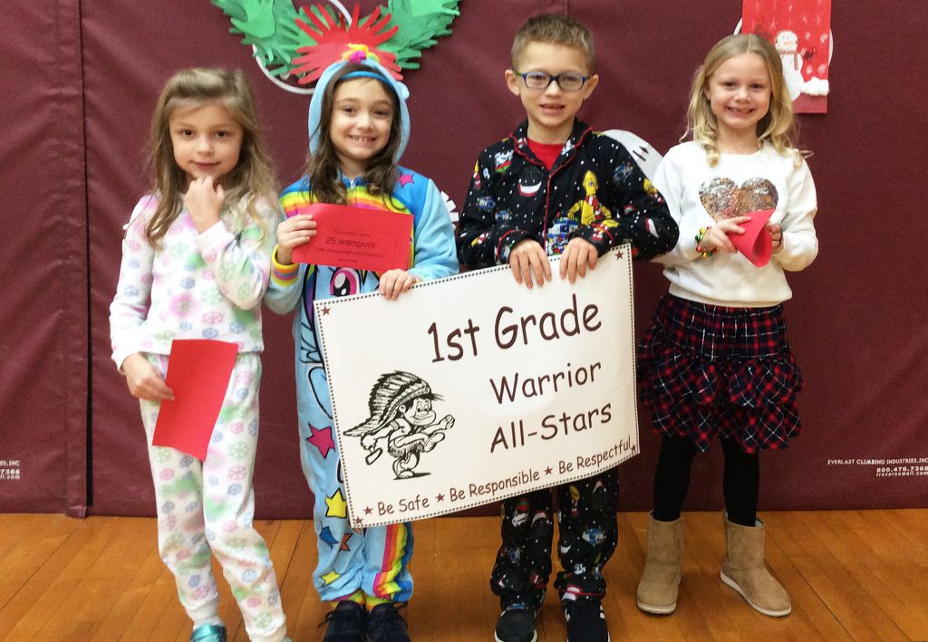 Three girls and a boy standing with first grade sign