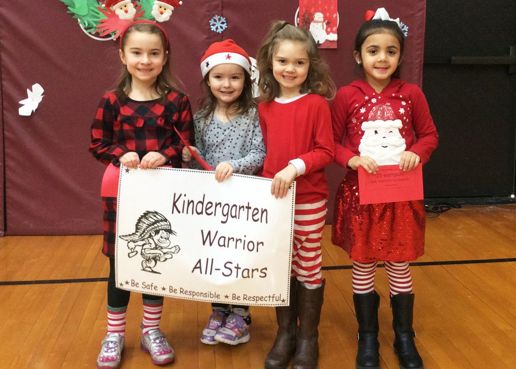Four students standing together with kindergarten sign