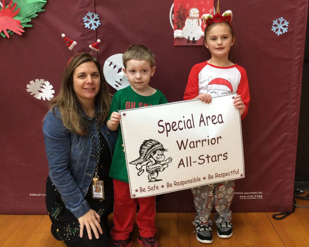 Two students and a teacher standing with specials sign