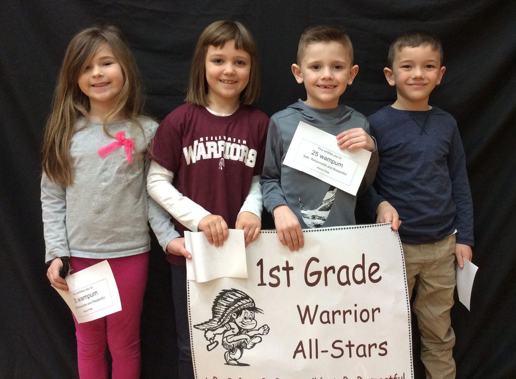 Four first grade students standing with Warrior All Star sign