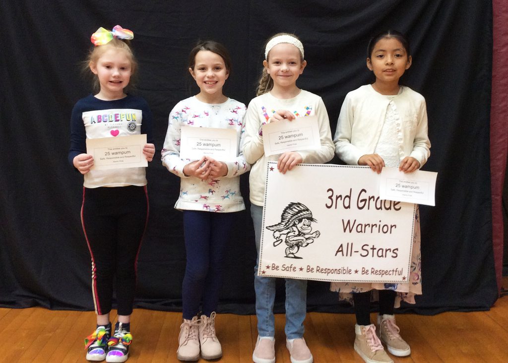 Four third grade students standing with warrior all star sign