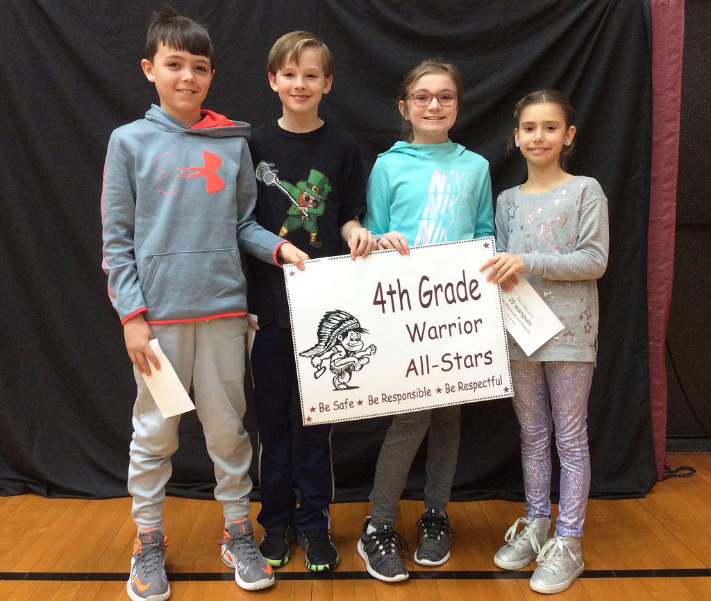 Four fourth grade students standing with warrior all star sign