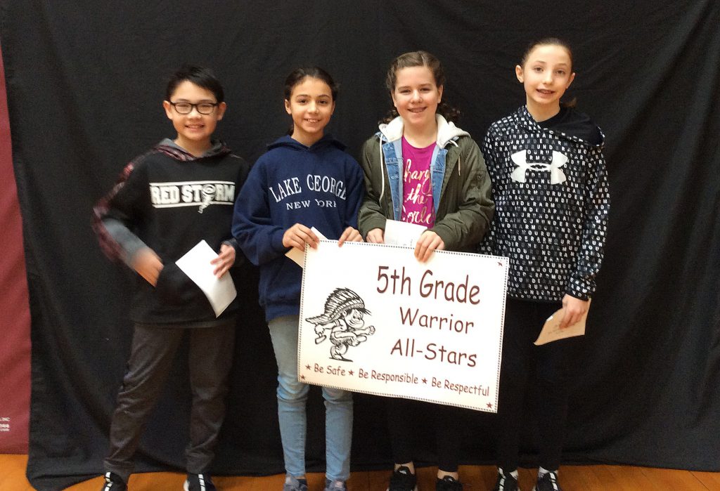 Four fifth grade students standing with fifth grade warrior all star sign