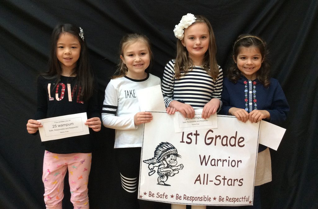 Four students standing with first grade warrior all-star sign