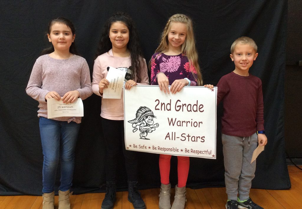 Four students standing with second grade warrior all-star sign