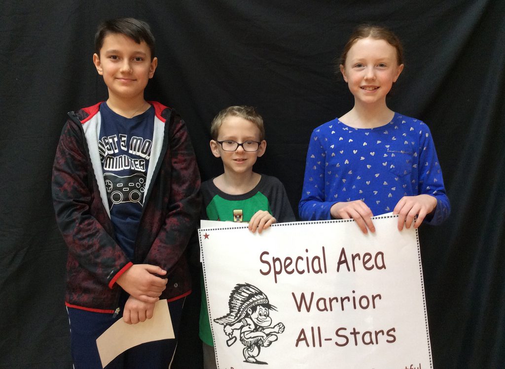 Three students standing with special area sign