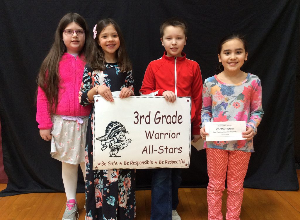 Four third grade students standing with warrior all-star sign