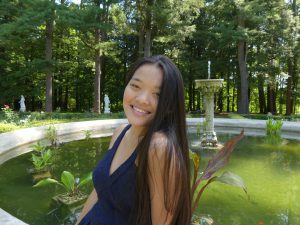 Headshot of student in front of a pond with a fountain