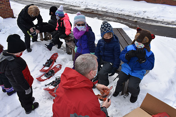 Superintendent and Assistant Principal help students put on snowshoes