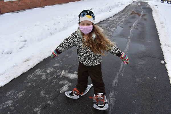 A happy snowshoeing student starts toward the trail