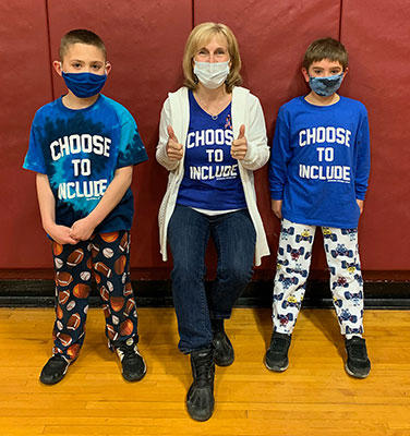 Superintendent standing with 2 students, all wearing Choose to Include shirts