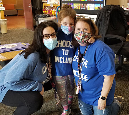 2 teachers with student, all wearing Choose to Include shirts