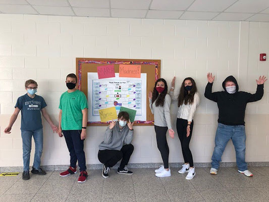 students in front of bulletin board showing their music brackets