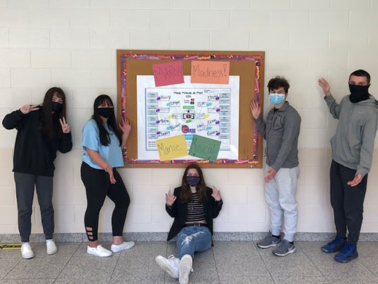 students in front of a bulletin board with their music brackets