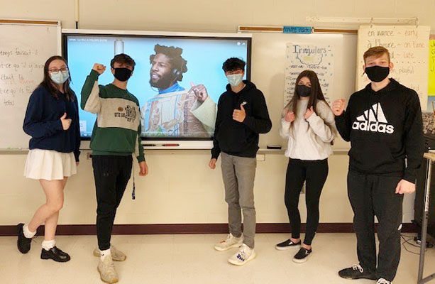 students in front of a video screen with a musician on it