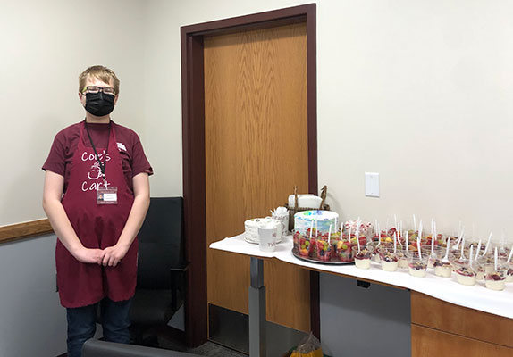 student standing next to table of food