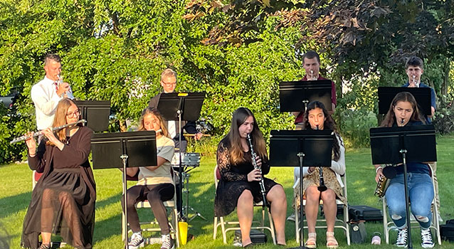 students and teacher playing instruments outside 