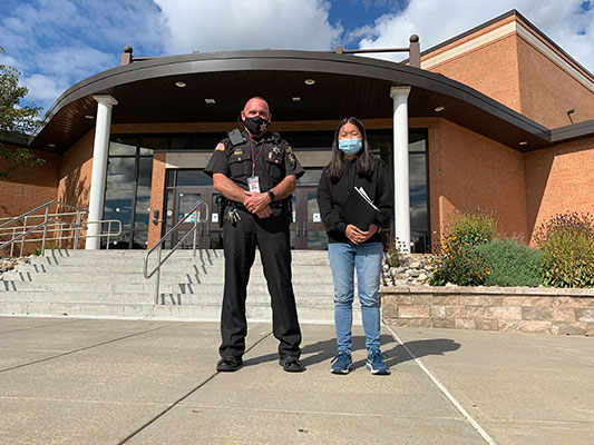 Deputy Lyons and Mei Lei Urbanski standing in front of HS entrance