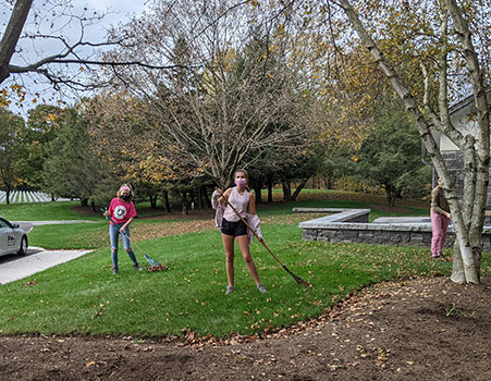 students raking grass