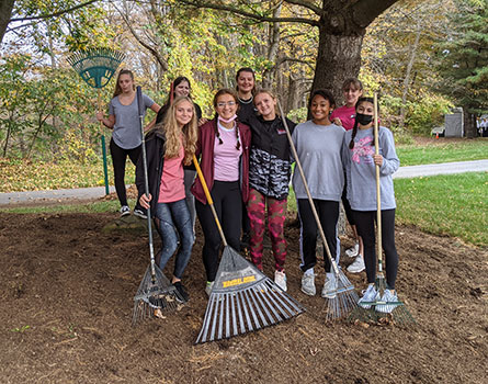 group of students holding rakes